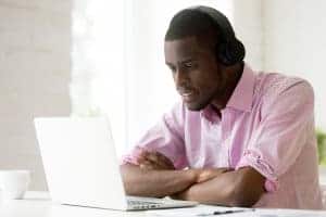 African American man wearing headphones taking to his online therapist during online therapy in Pennsylvania with Synergy eTherapy. Telehealth and online counseling can help you heal too!