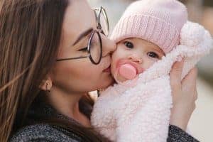 Mom kissing baby outside in Chicago, IL | Online Therapy in Illinois | Synergy eTherapy