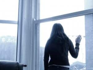woman with bipolar depression stares out the window. She receives online depression treatment and online counseling with synergy etherapy an online counseling practice