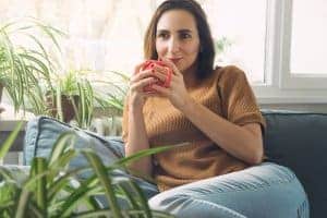 depressed woman finds relief from the symptoms of depression and sits on the couch with coffee. She had online depression treatment with synergy etherapy an online counseling practice.