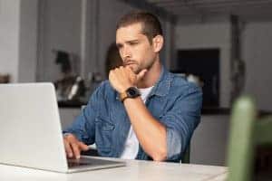 man with anxiety sits at his computer in his home attending an online counseling session for anxiety treatment with a Synergy eTherapy therapist