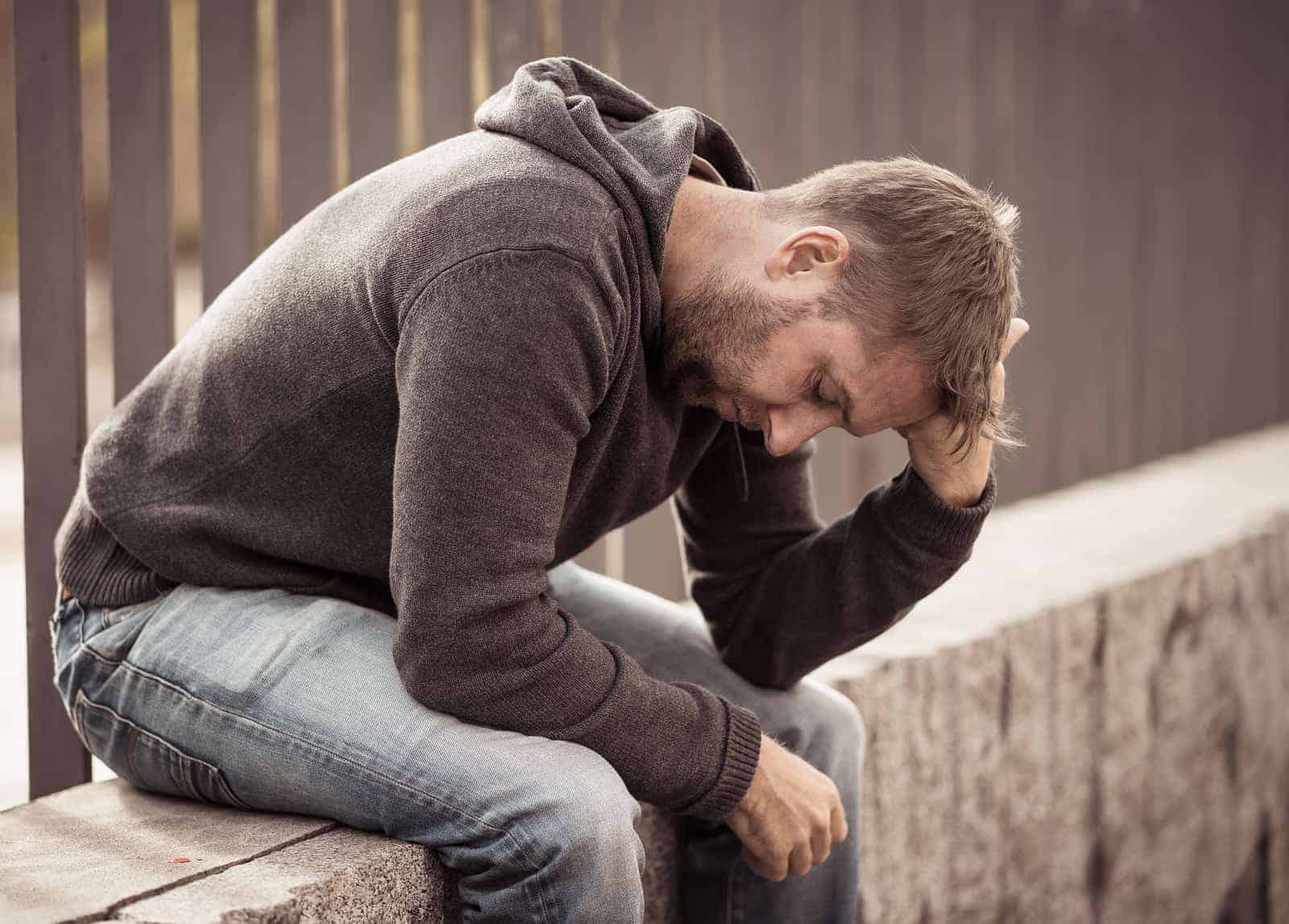 anxious young man sits with his head in his hands before getting anxiety treatment from Synergy eTherapy which is an online counseling practice