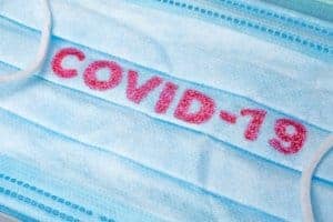 mask with the word COVID-19 on it illustrating the severity of the coronavirus pandemic | begin online therapy or telehealth for anxiety and other concerns with Syngergy eTherapy