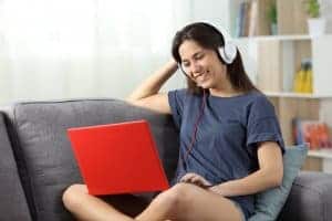 happy teen sits at her laptop during online therapy in New Jersey for online teen and online family therapy with a Synergy eTherapy therapist